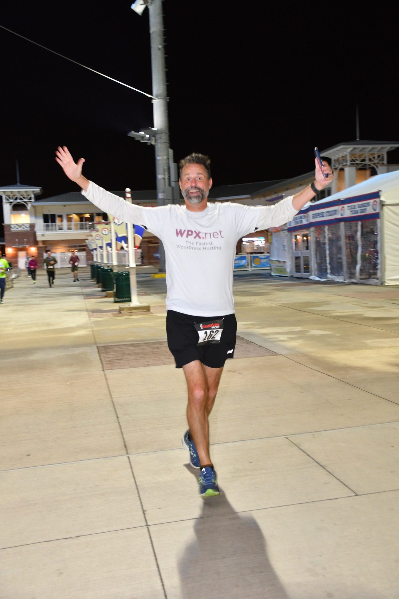 Patrick finishing the Spring Training 5K, arms raised